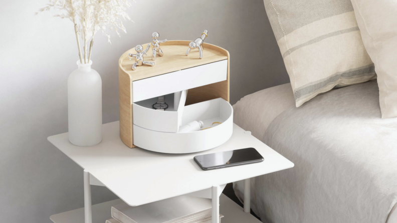 White wooden bedside table organizer from OXO next to bed on nightstand table.